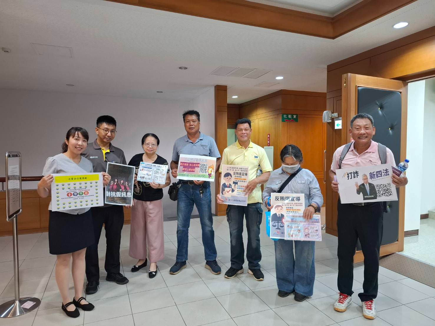 臺中市政府法制局廉政反詐騙及消費者保護法宣導民眾手持廉政宣導手牌合影